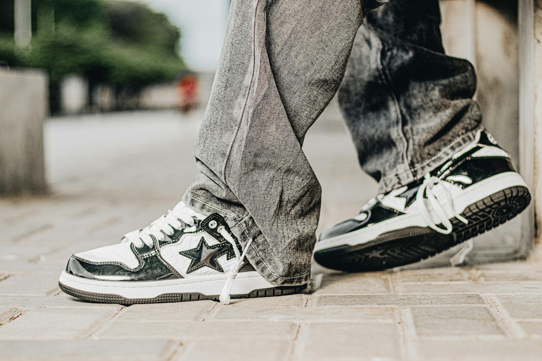 Close-up of stylish black and white sneakers worn with jeans on a city street.
